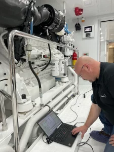 One of Motortec's expert team members using a laptop as part of their CAT yacht engine inspections.